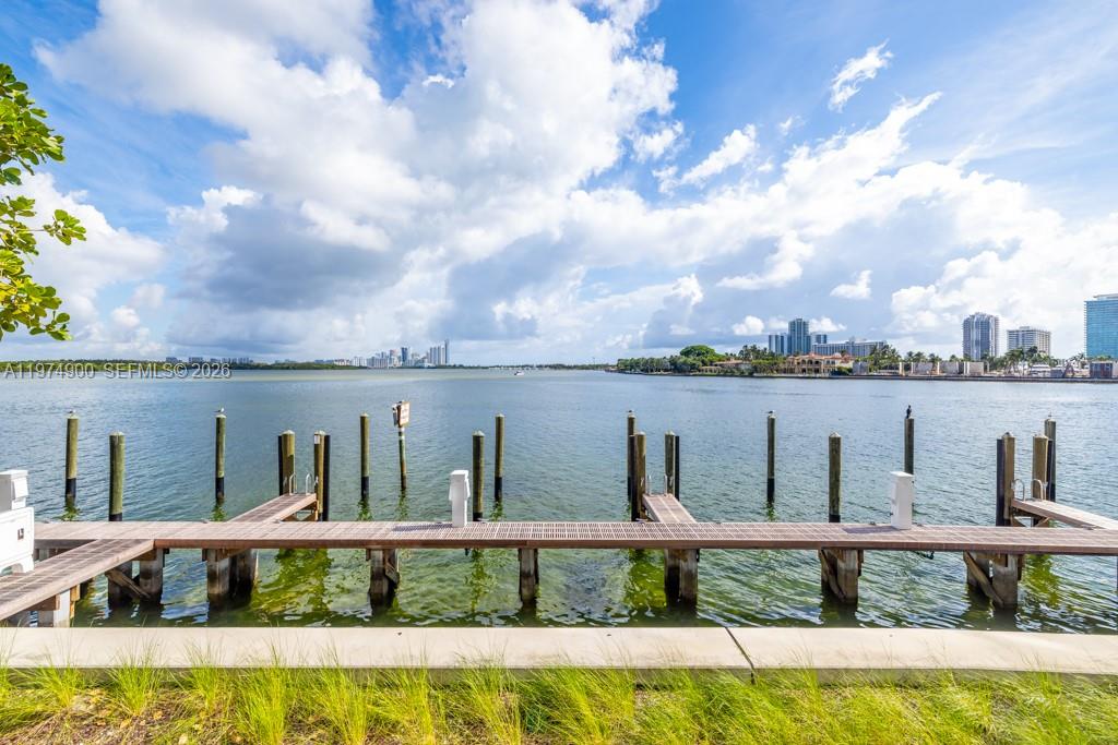 A wooden dock extends into a calm bay with a city skyline in the distance — 1135 103rd # 307, Bay Harbor Islands FL 33154, BAY HARBOR ISLANDS, FL