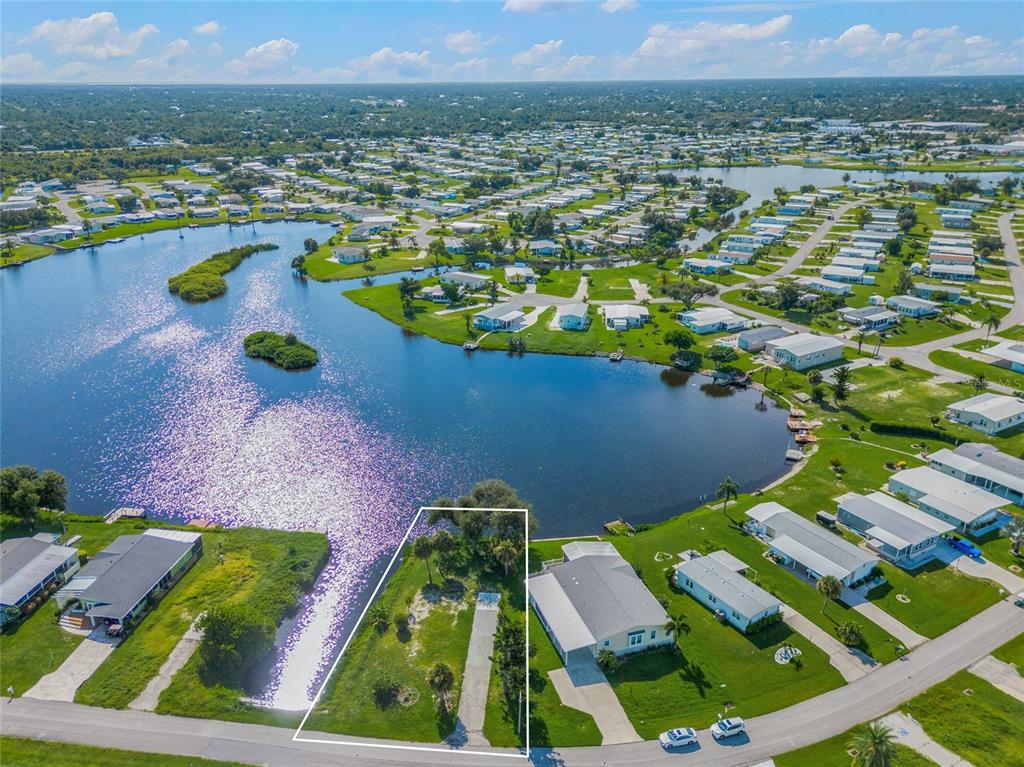 An aerial view shows a vacant waterfront lot outlined in white within a residential community — 1329 BLUE HERON DRIVE, ENGLEWOOD, FL
