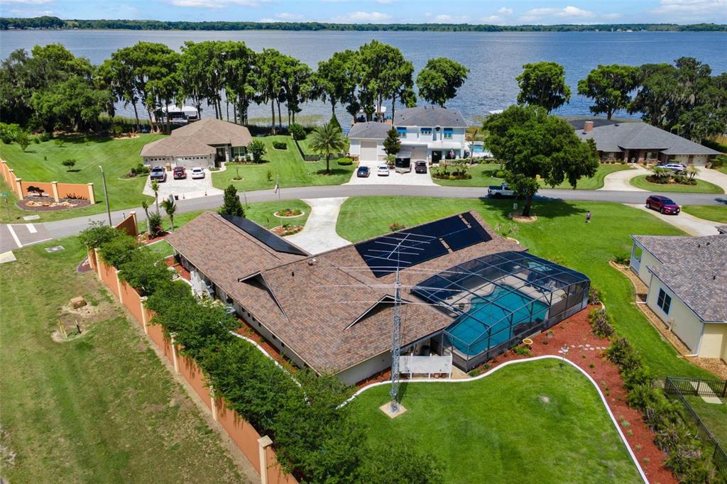 An aerial view shows a house with solar panels, a screened pool, and a tall antenna — 26515 SAVAGE CIRCLE, HOWEY IN THE HILLS, FL