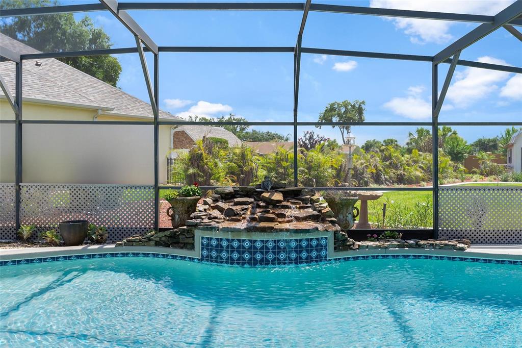 A swimming pool with a stone waterfall feature inside a screened-in patio area — 26515 SAVAGE CIRCLE, HOWEY IN THE HILLS, FL