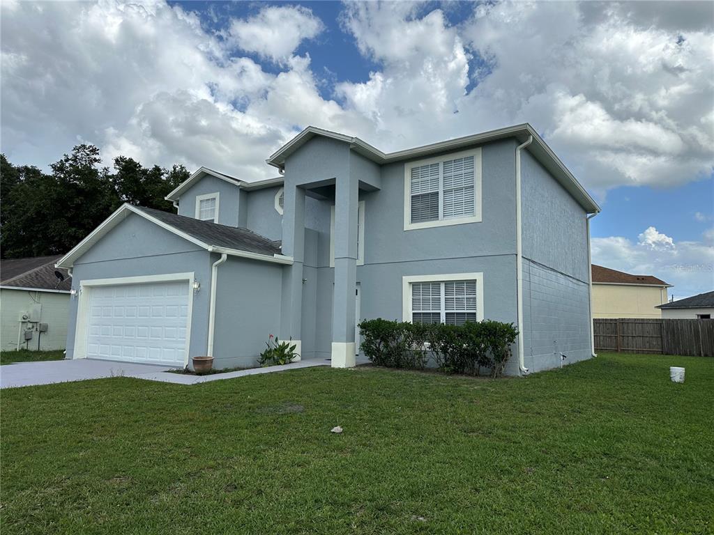 A two-story, light blue house with a two-car garage and a grassy front yard — 747 PELICAN COURT, POINCIANA, FL