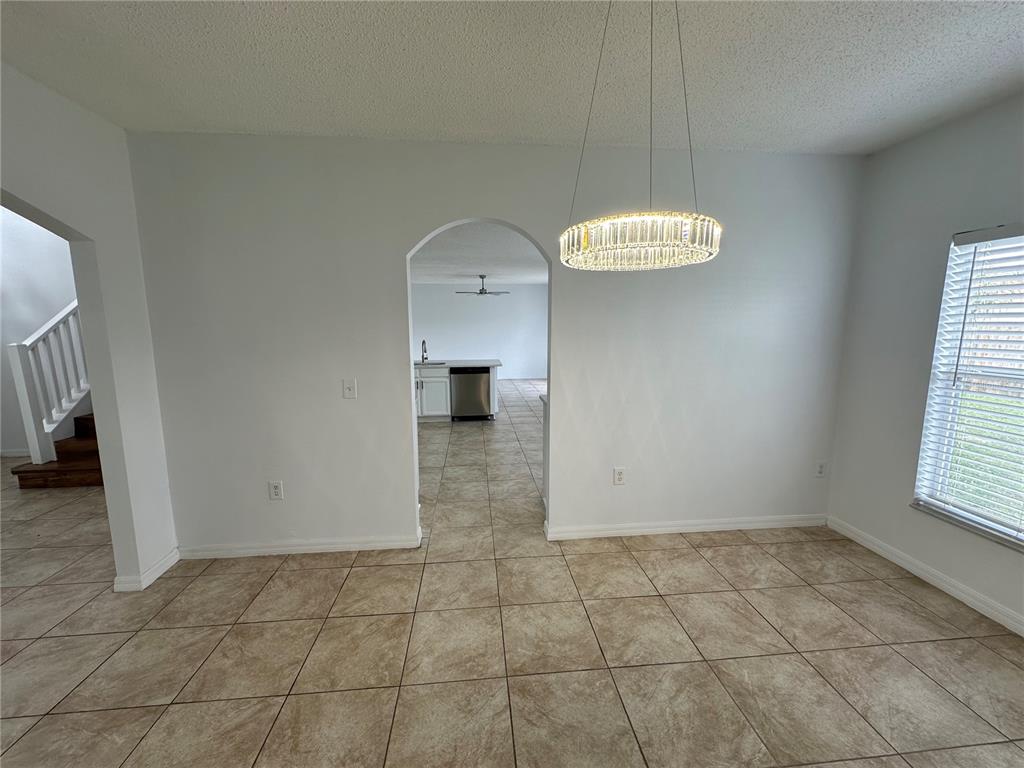 A dining area with tile flooring and a crystal chandelier leads to a kitchen — 747 PELICAN COURT, POINCIANA, FL