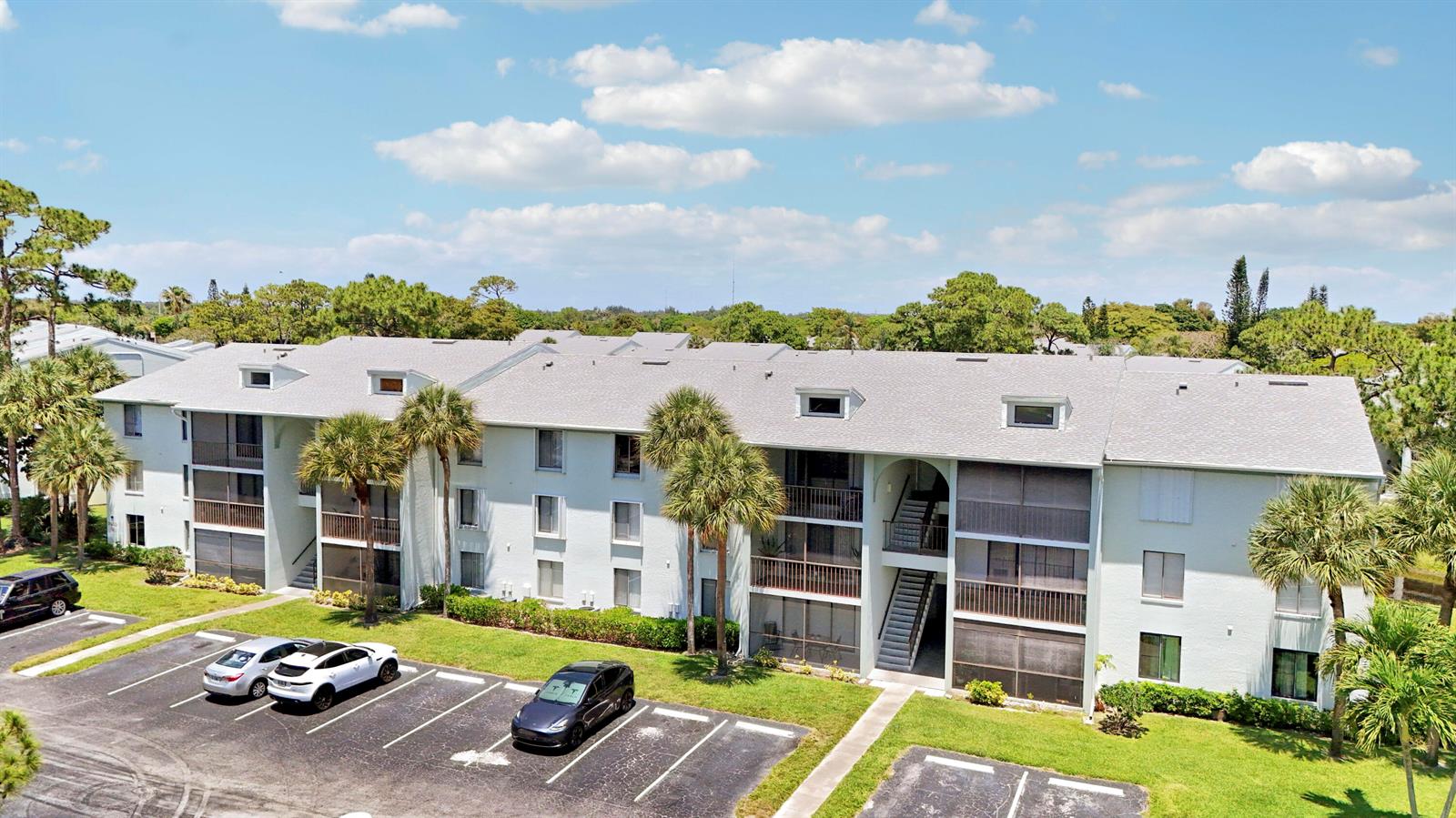 An aerial view of a multi-story apartment building with a parking lot in front — 3630 Alder Drive # E2, West Palm Beach FL 33417, WEST PALM BEACH, FL