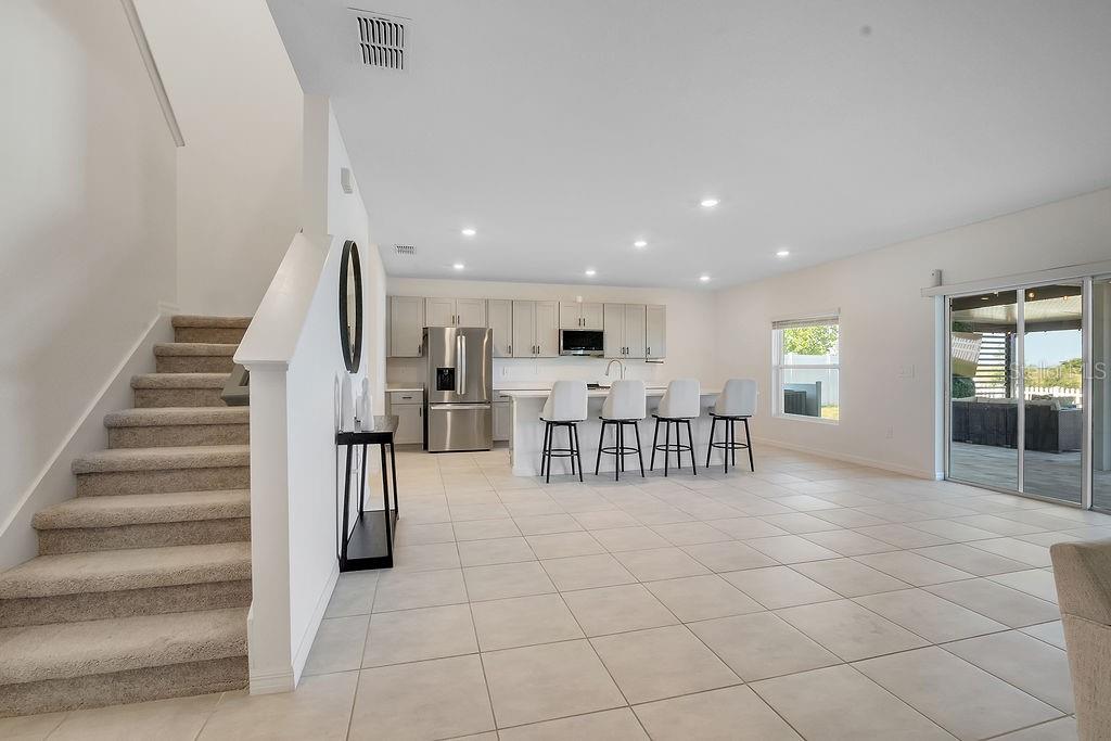 A spacious open-concept living room features a large sectional sofa, tile floors, and kitchen area — 1033 CALICO POINTE CIRCLE, GROVELAND, FL