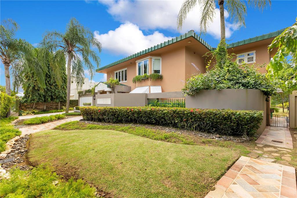 A two-story tan house with a green roof, palm trees, and a manicured hedge — A2 MONTEBELLO STREET, GUAYNABO, PR