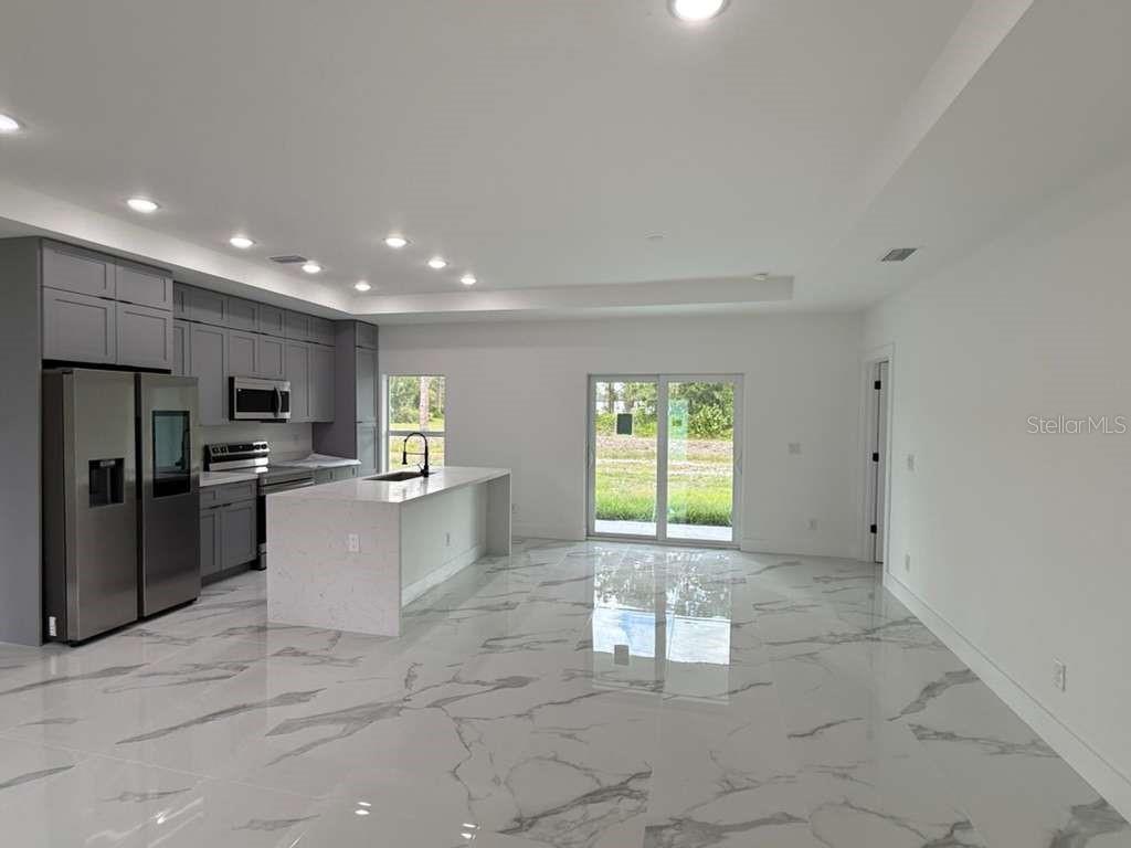 A modern kitchen with gray cabinets, a white island, and marble-patterned tile flooring — 765 PUCCINI AVE S, LEHIGH ACRES, FL