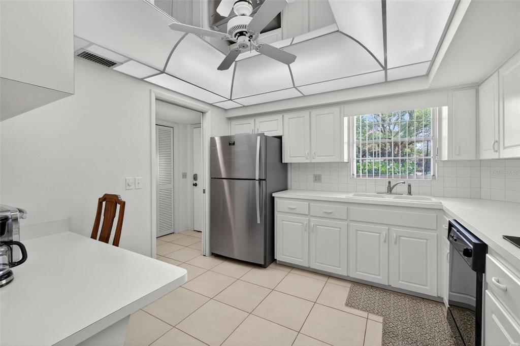 A kitchen features white cabinetry, stainless steel appliances, tile flooring, and a tray ceiling — 2440 WORLD PARKWAY BOULEVARD UNIT 6, CLEARWATER, FL