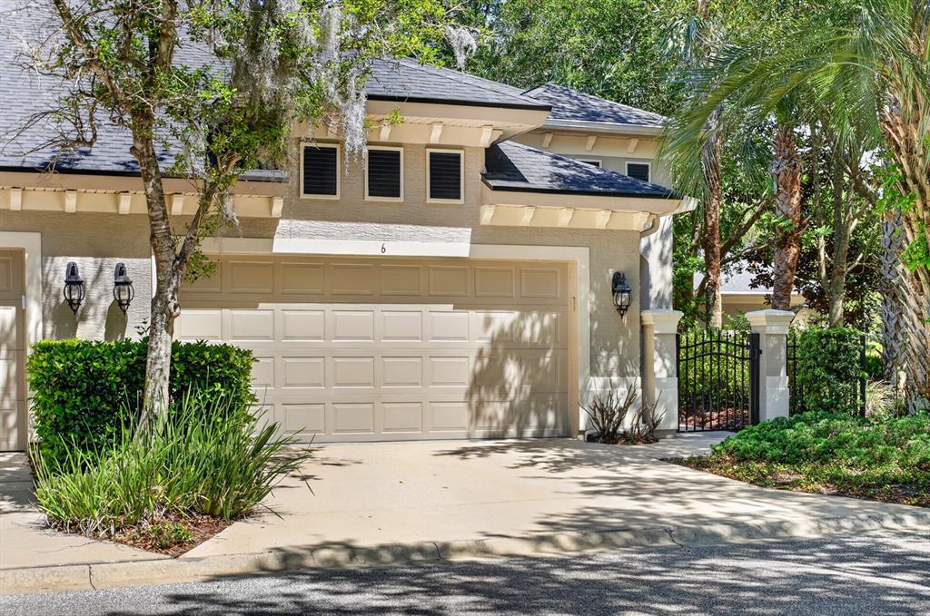 A beige two-car garage with a number six above the door and surrounding landscaping — 6 RIVER POINT DRIVE, PALM COAST, FL