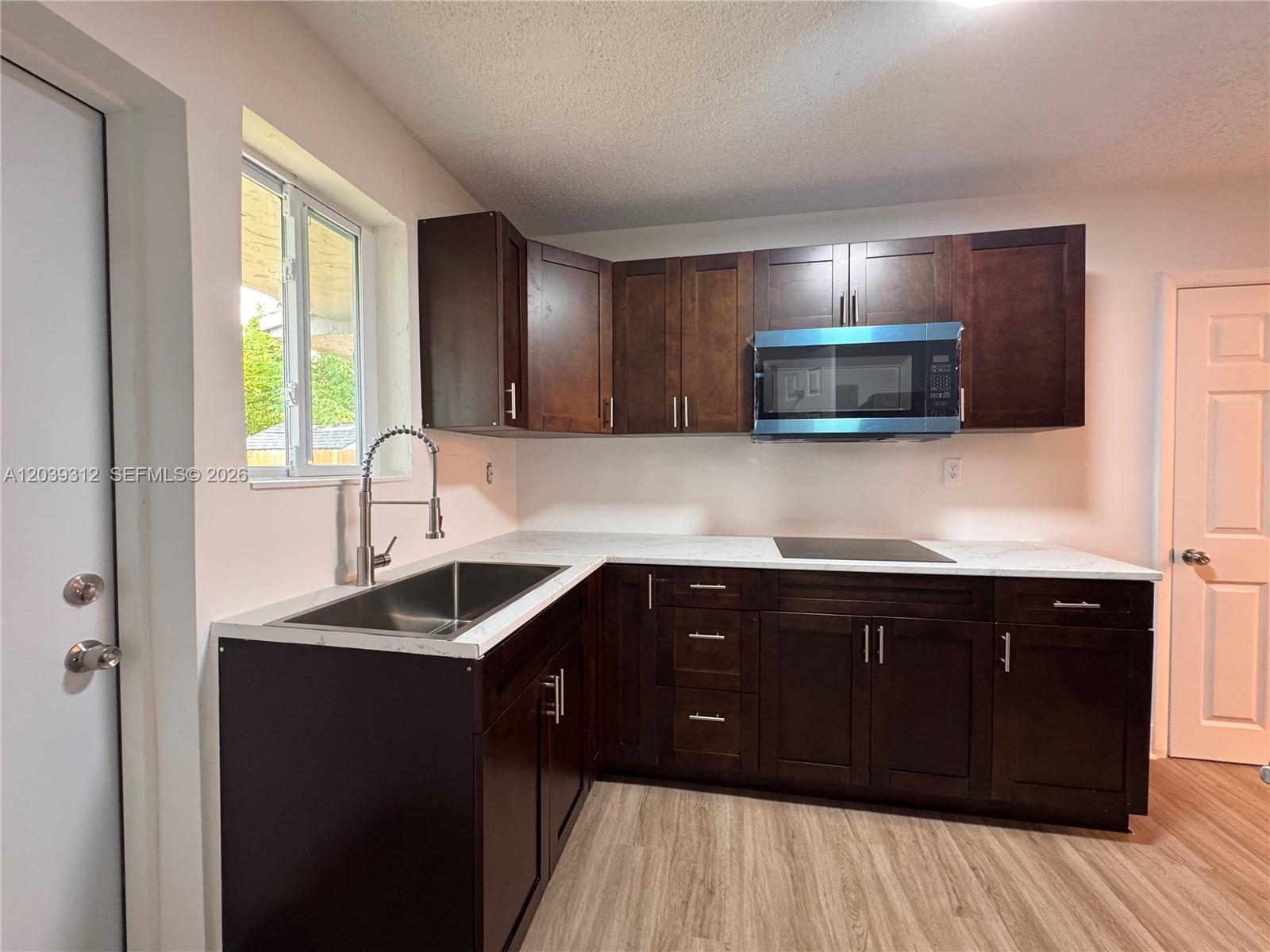 A kitchen features dark wood cabinets, white countertops, a stainless steel sink, and a microwave — 3632 SW 87th Ave, Miami FL 33165, MIAMI, FL