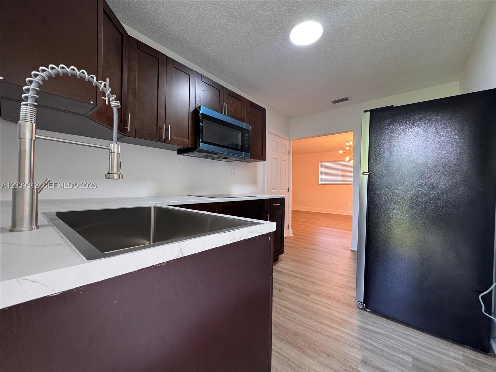 A kitchen features dark wood cabinets, white countertops, a stainless steel sink, and black appliances — 3632 SW 87th Ave, Miami FL 33165, MIAMI, FL