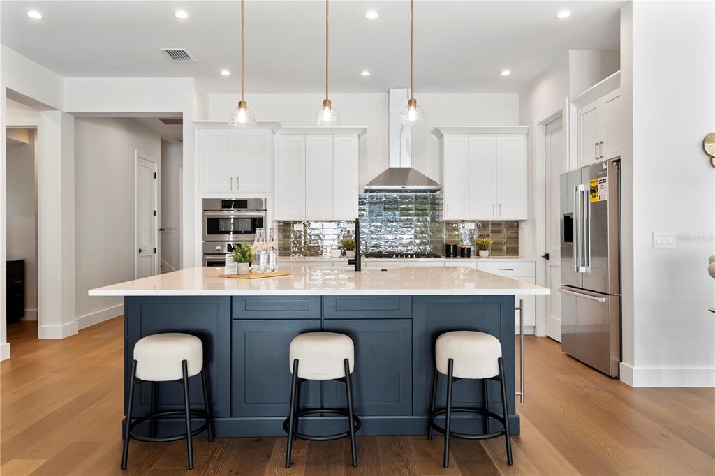 A modern kitchen features a dark blue island with three stools and white upper cabinets — 1606 MILLER AVENUE, WINTER PARK, FL