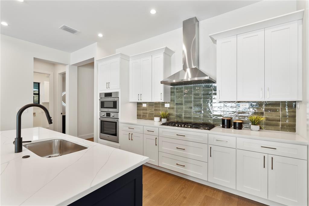 A modern kitchen features white cabinets, a dark blue island, and a green tiled backsplash — 1606 MILLER AVENUE, WINTER PARK, FL