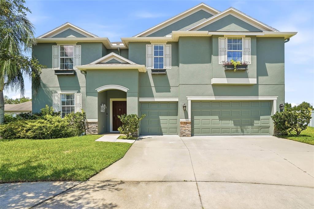 A two-story house with green stucco siding, a concrete driveway, and a two-car garage — 3987 ROUND TABLE COURT, LAND O LAKES, FL