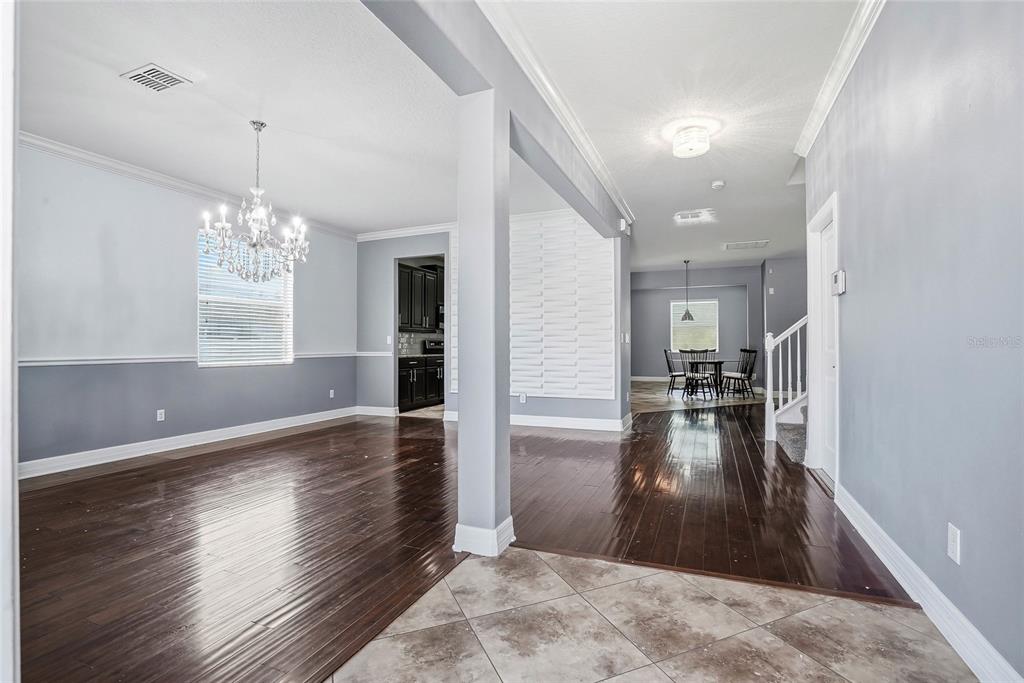 An open-concept living area features dark hardwood floors, a crystal chandelier, and a dining nook — 3987 ROUND TABLE COURT, LAND O LAKES, FL