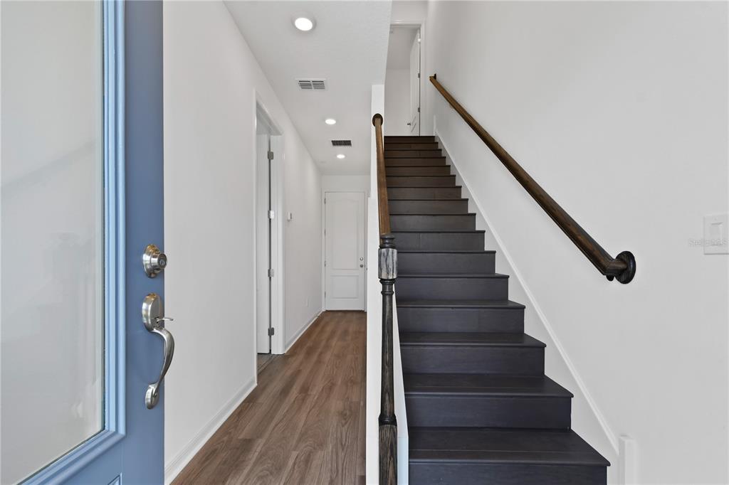 An entryway features a blue front door, wood-look flooring, and a dark-stained staircase — 13140 BOVET AVENUE, ORLANDO, FL