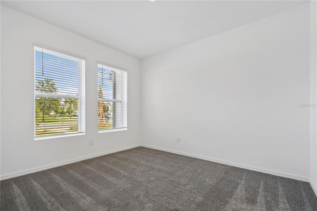 An empty bedroom features white walls, gray carpeting, and two windows with white blinds — 13140 BOVET AVENUE, ORLANDO, FL
