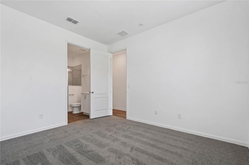 A bedroom with gray carpet, white walls, and an open door leading to a bathroom — 13140 BOVET AVENUE, ORLANDO, FL