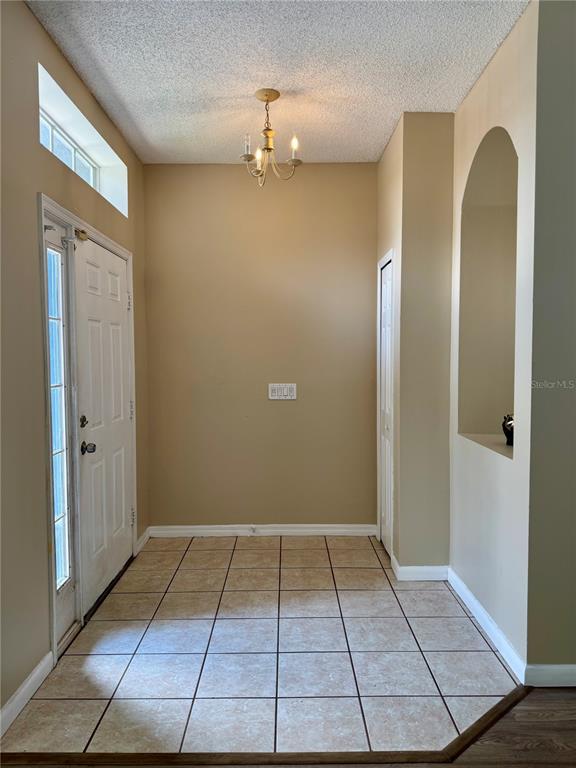 An entryway features a tiled floor, a chandelier, a front door, and an arched wall niche — 14605 KRISTENRIGHT LANE, ORLANDO, FL