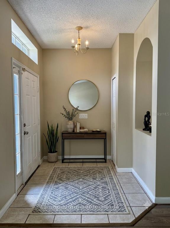 An entryway features a tiled floor, a console table with a mirror, and a chandelier — 14605 KRISTENRIGHT LANE, ORLANDO, FL