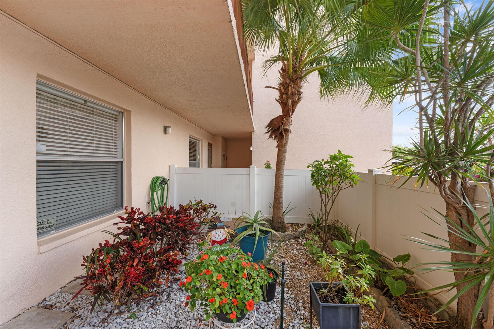 A small outdoor patio area features a gravel garden, potted plants, and a white fence — 14527 Bonaire Boulevard # 109, Delray Beach FL 33446, DELRAY BEACH, FL
