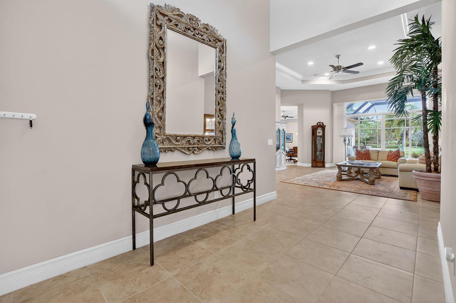 A foyer with a console table and ornate mirror leads into a spacious living room — 12133 Glacier Bay Drive, Boynton Beach FL 33473, BOYNTON BEACH, FL