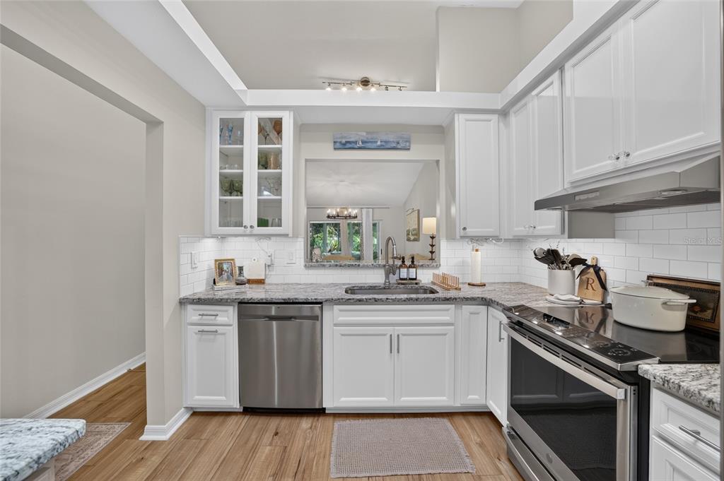 A kitchen features white cabinets, granite countertops, stainless steel appliances, and a subway tile backsplash — 2429 SE 18TH CIRCLE, OCALA, FL