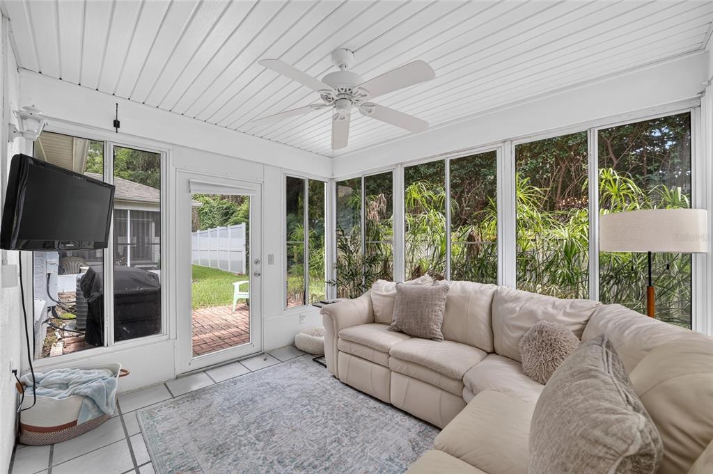 A sunroom features a white sectional sofa, tile flooring, a ceiling fan, and large windows — 2429 SE 18TH CIRCLE, OCALA, FL