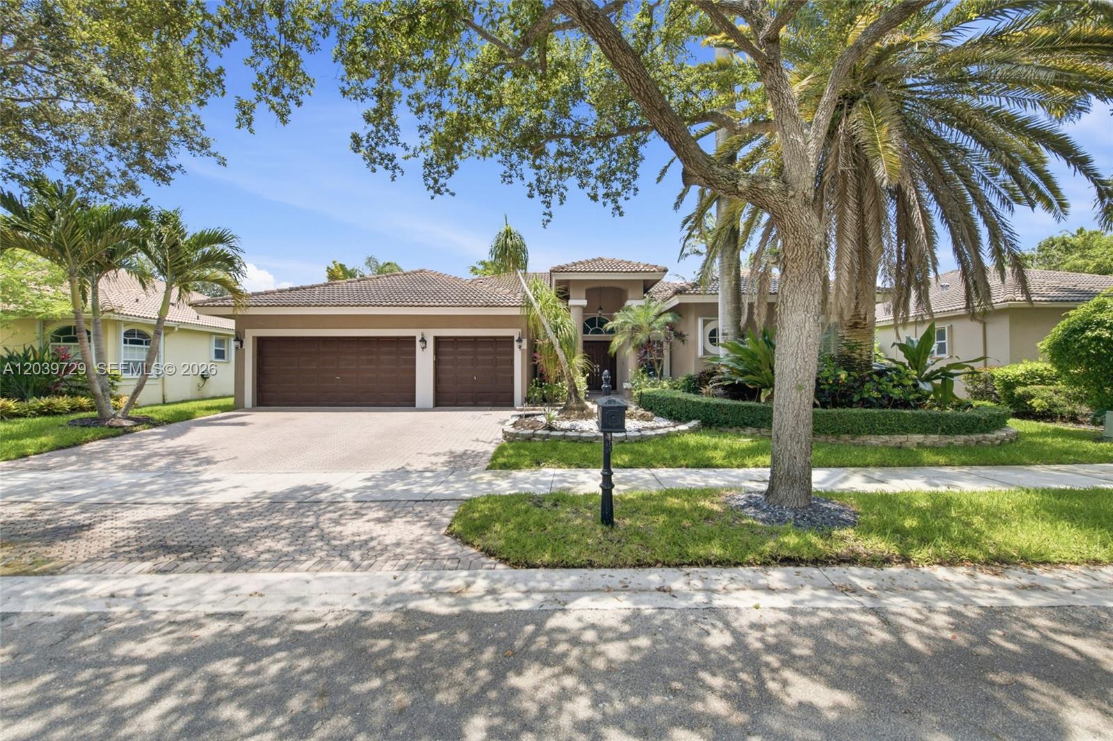 A single-story house with a brown tile roof, three-car garage, and palm trees — 3725 Oak Ridge Ln, Weston FL 33331, WESTON, FL