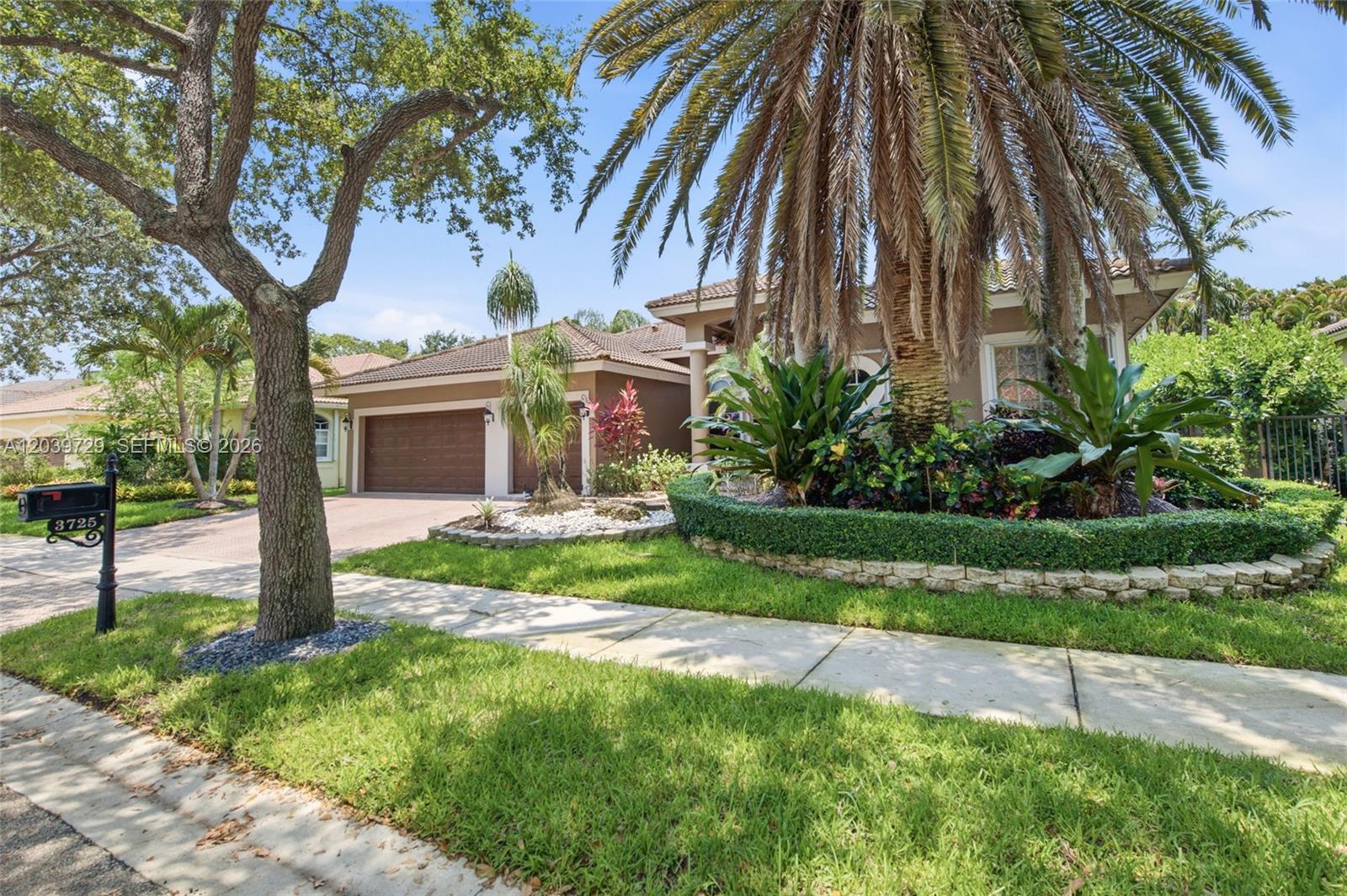 A single-story house with a two-car garage, palm trees, and a landscaped front yard — 3725 Oak Ridge Ln, Weston FL 33331, WESTON, FL