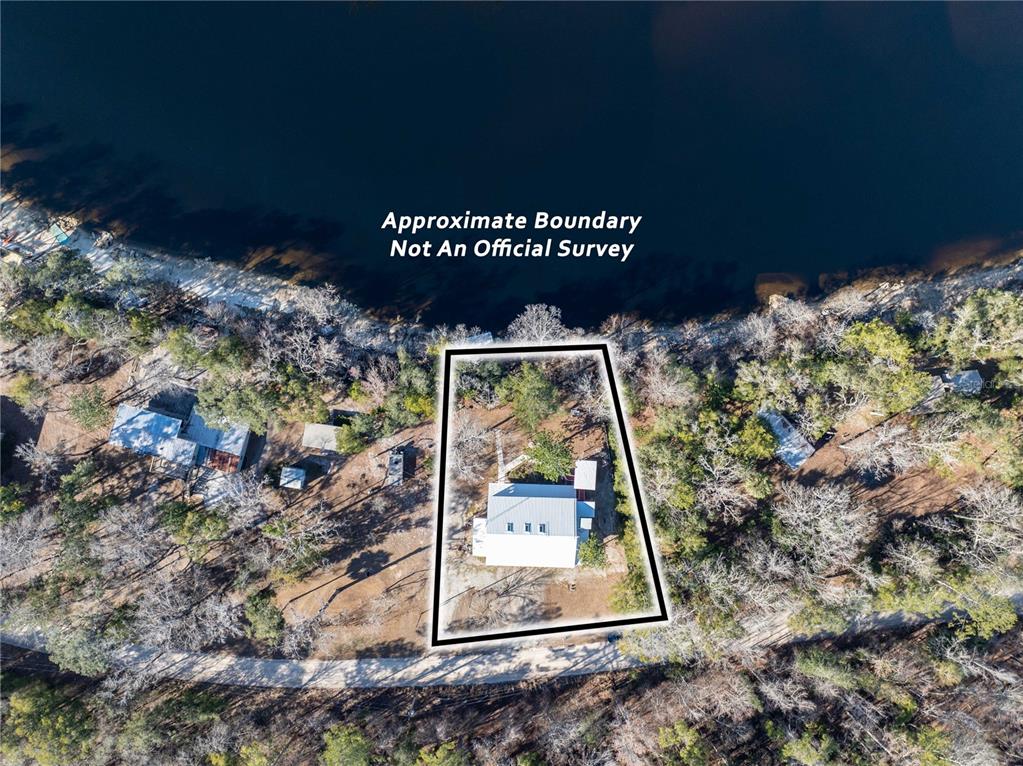An aerial view shows a house on a wooded lot bordering a body of water — 30009 81ST PLACE, BRANFORD, FL