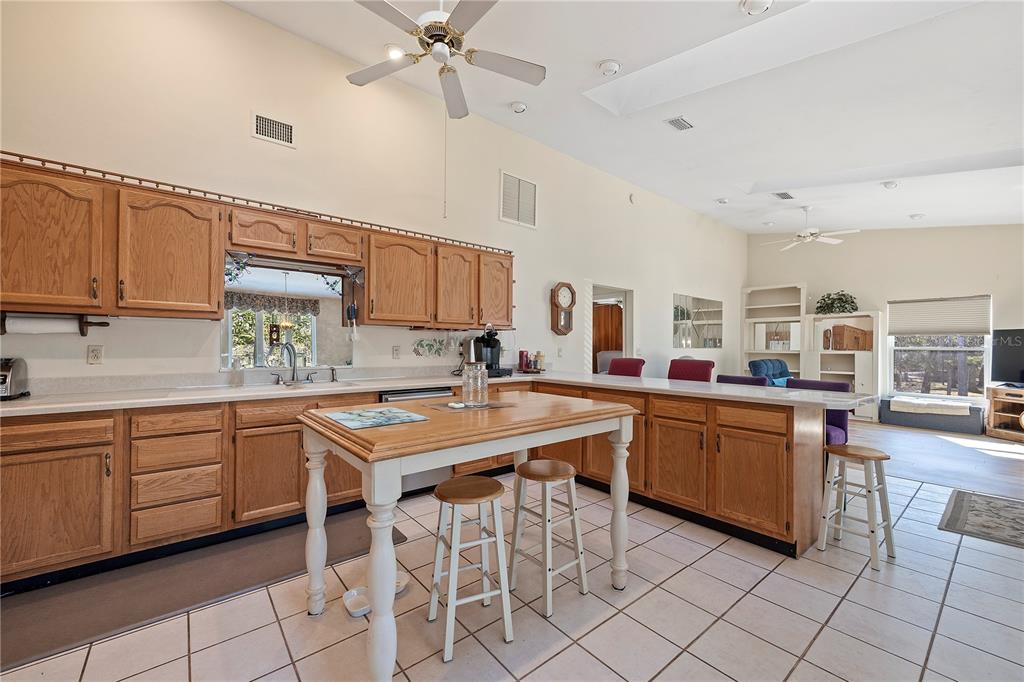 A kitchen with oak cabinets, a central island, and a breakfast bar overlooks a living area — 30009 81ST PLACE, BRANFORD, FL