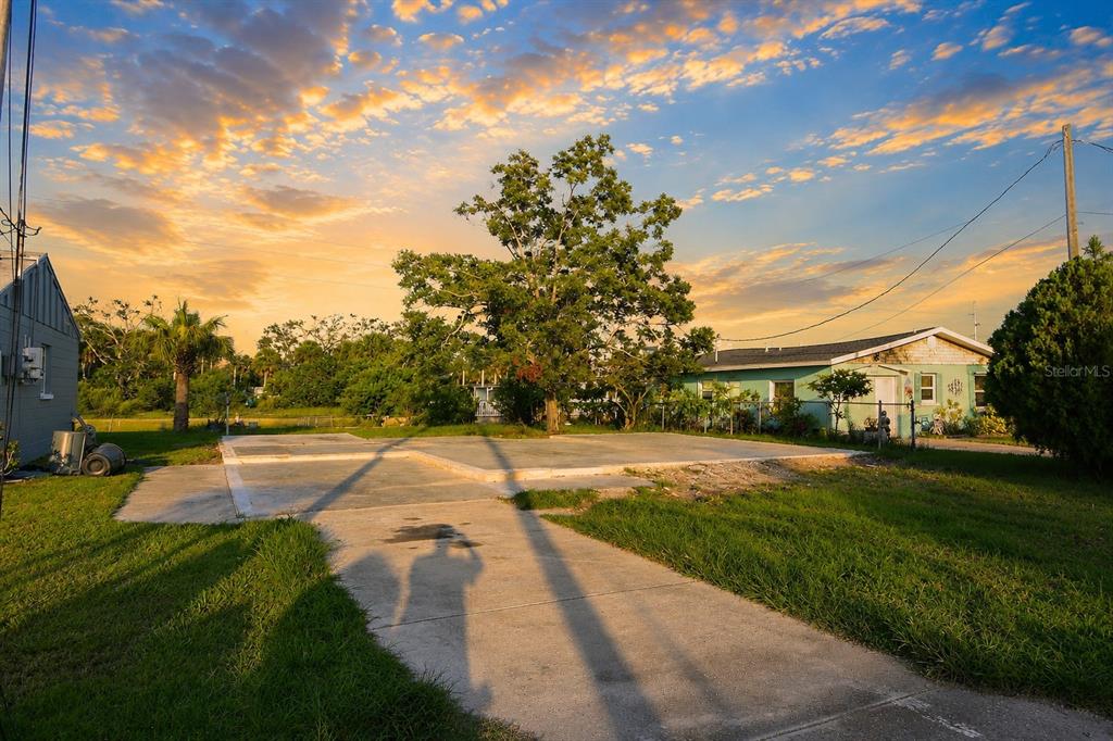 A concrete slab sits in a grassy yard next to a house at sunset — 13900 MURIEL AVENUE, HUDSON, FL