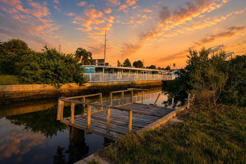 A wooden dock sits on a canal in front of a mobile home at sunset — 13900 MURIEL AVENUE, HUDSON, FL