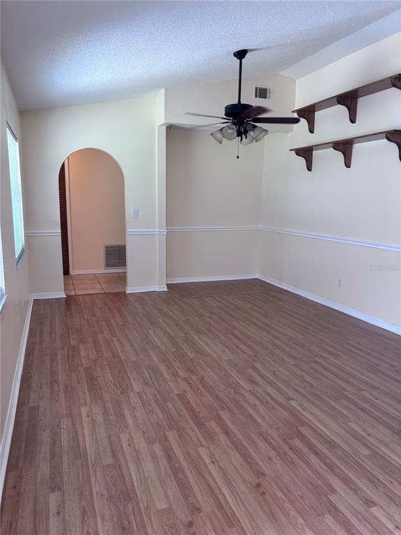 A living room features wood-look flooring, a ceiling fan, and two wall-mounted wooden shelves — 4907 NE 6TH STREET, OCALA, FL