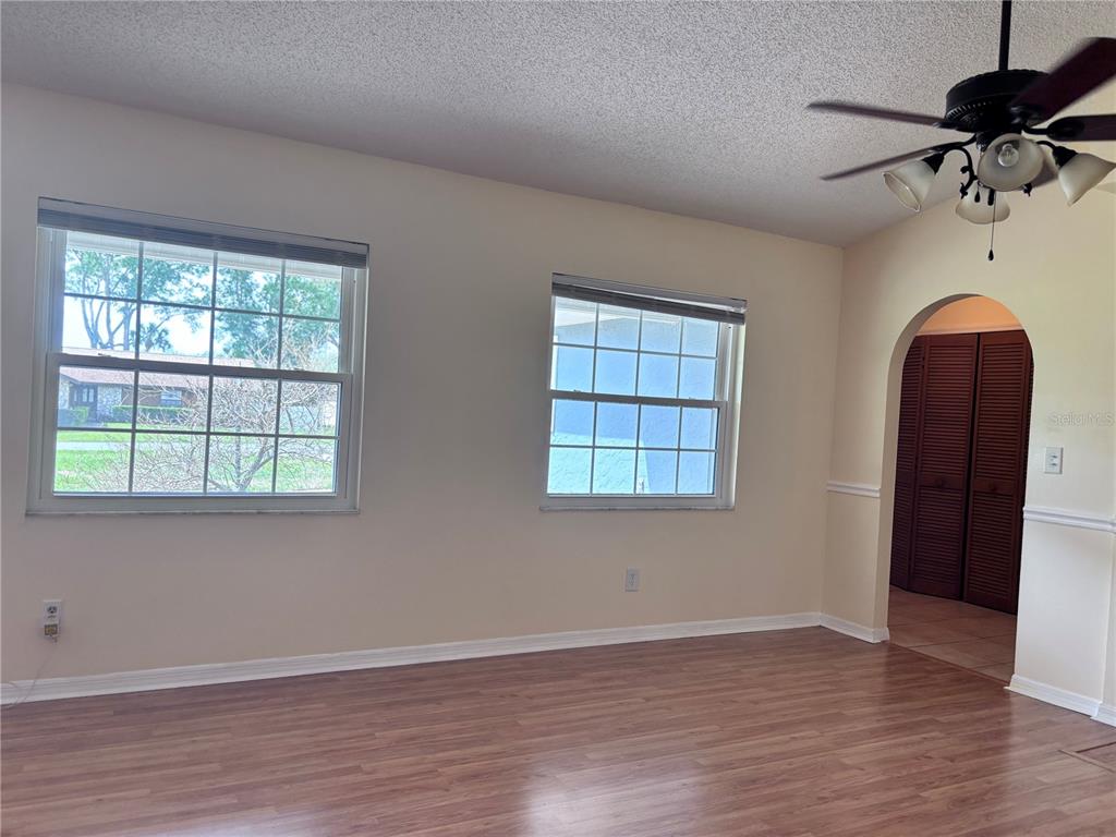 A room with wood-look flooring, two windows, and an arched doorway leading to a closet — 4907 NE 6TH STREET, OCALA, FL