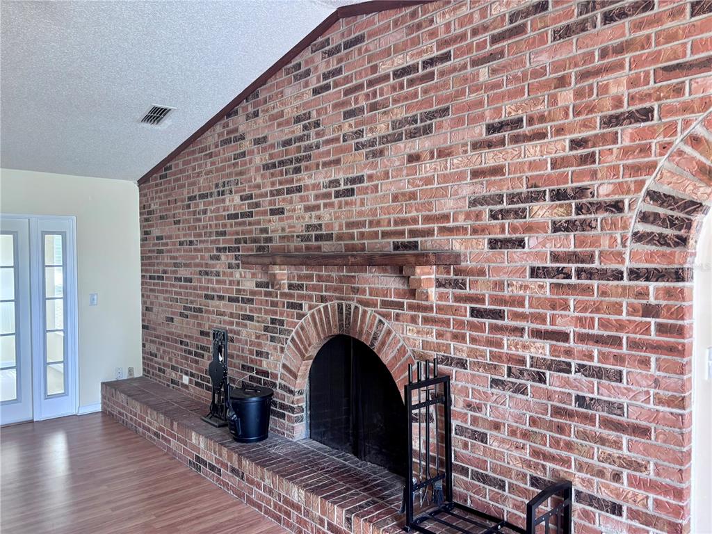 A large red brick fireplace with an arched opening and wooden mantel in a living room — 4907 NE 6TH STREET, OCALA, FL