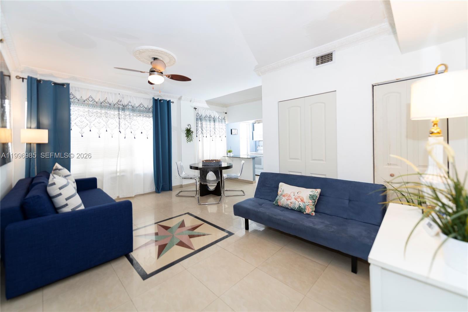 A living room features two blue sofas, a dining table, and tile flooring — 918 Ocean Dr # 202, Miami Beach FL 33139, MIAMI BEACH, FL