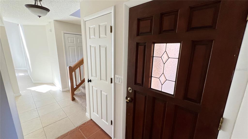 An interior entryway features a dark wood front door, a white closet door, and stairs — 35 CAPTAINS WALK, PALM COAST, FL