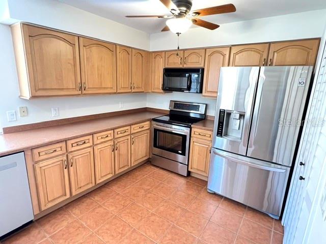 A kitchen features light wood cabinets, stainless steel appliances, and terracotta-colored tile flooring — 35 CAPTAINS WALK, PALM COAST, FL