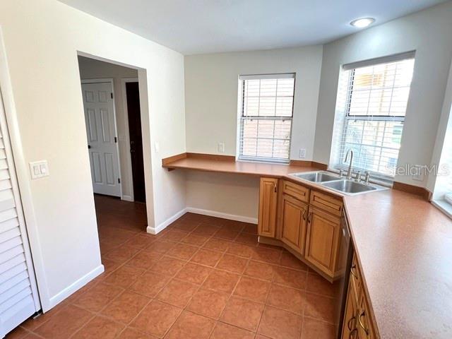 A kitchen features light wood cabinets, a double sink, and terracotta tile flooring — 35 CAPTAINS WALK, PALM COAST, FL
