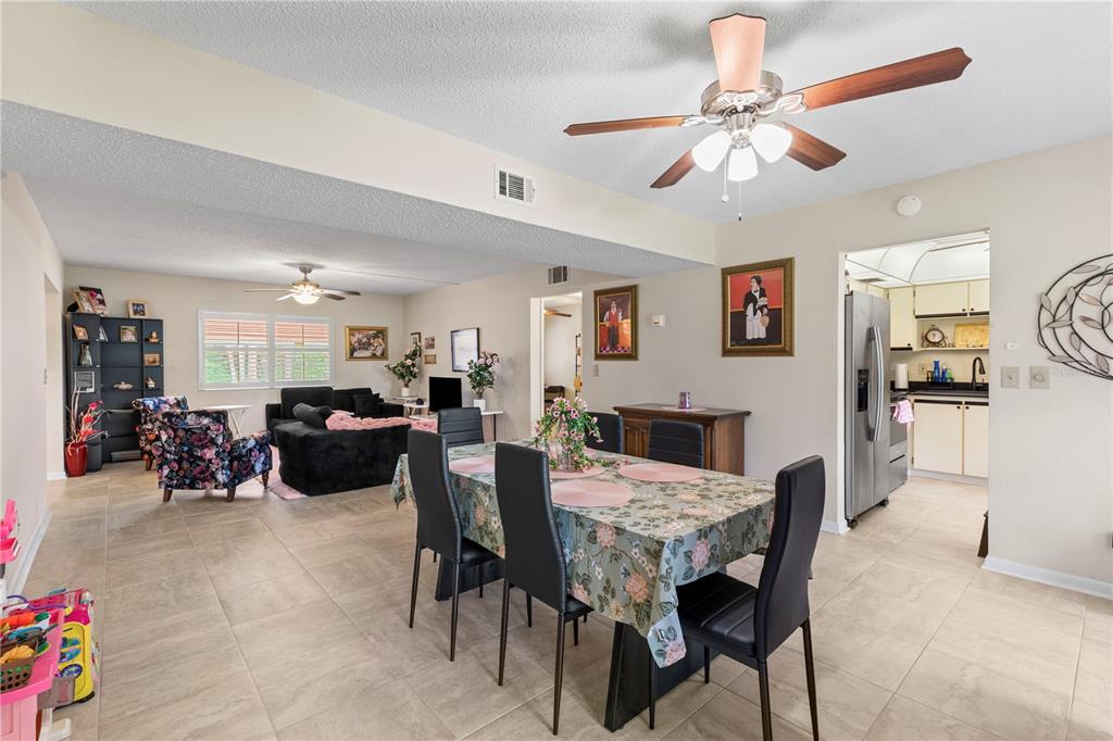 An open-concept dining and living area features tile flooring, a ceiling fan, and neutral walls — 275 INDIGO DRIVE UNIT 104, DAYTONA BEACH, FL