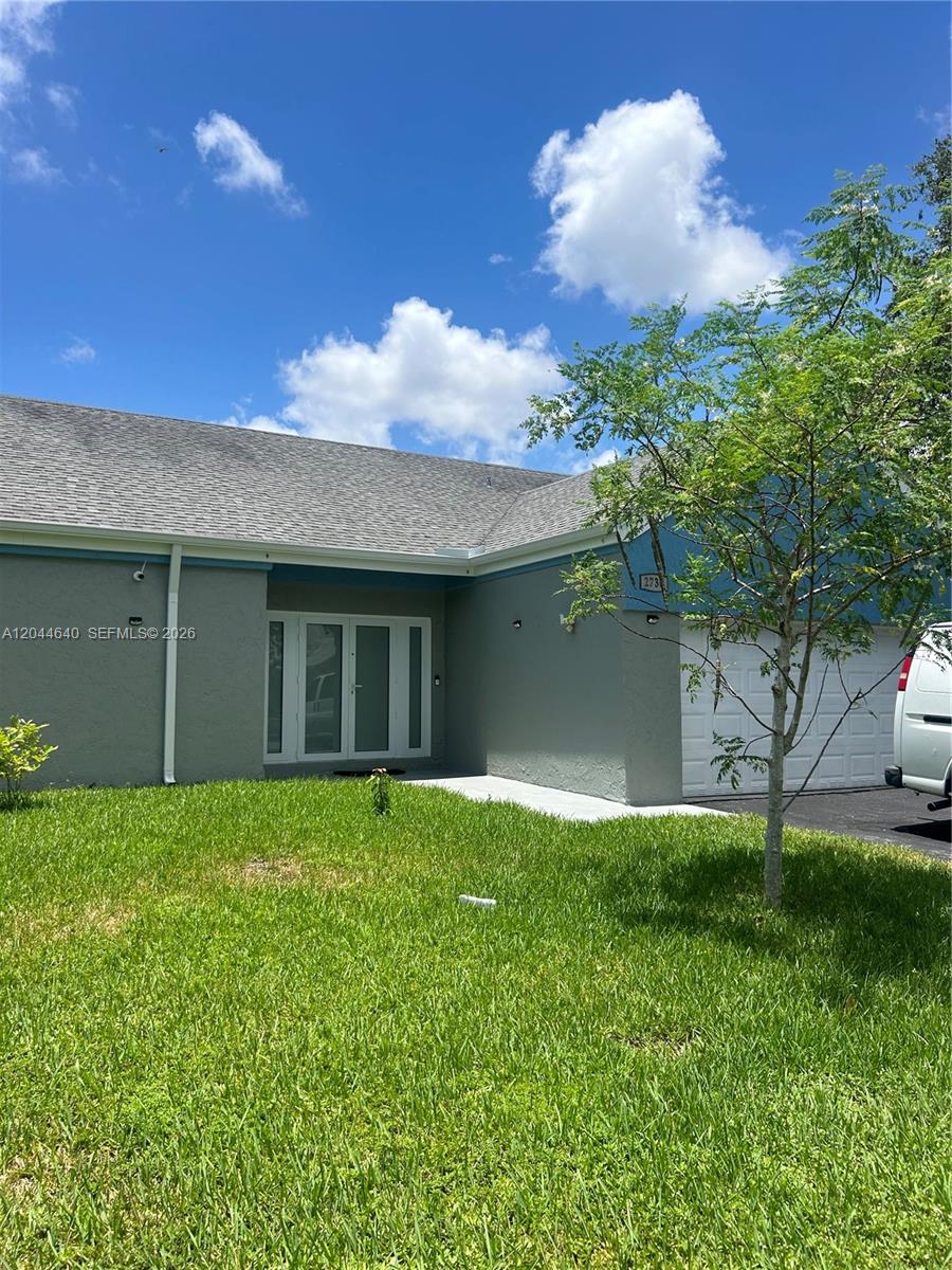 The exterior of a single-story house features gray stucco walls, a shingled roof, and a garage — 2730 Cypress Ave, Miramar FL 33025, MIRAMAR, FL
