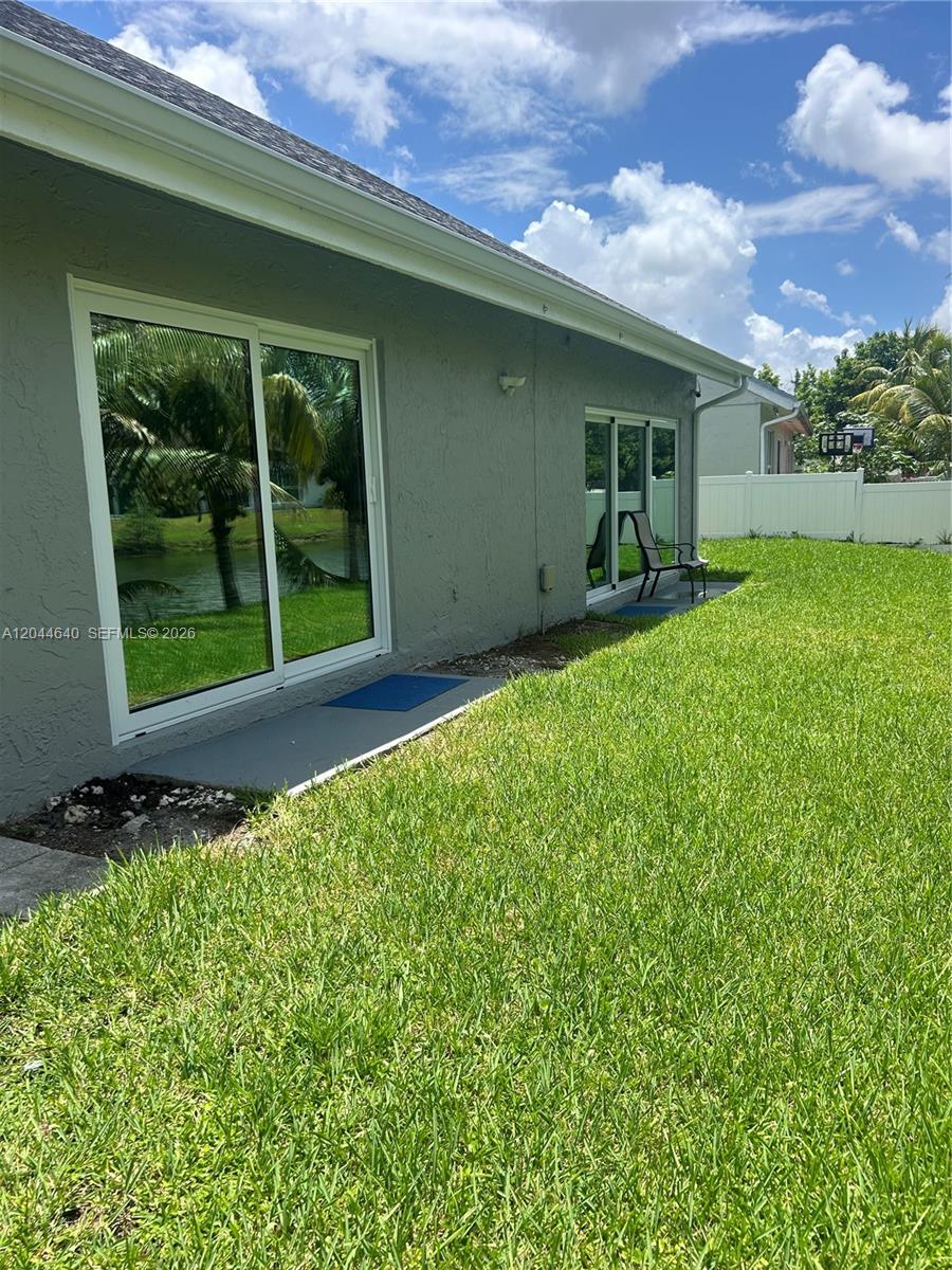 The exterior of a gray house features sliding glass doors and a grassy backyard — 2730 Cypress Ave, Miramar FL 33025, MIRAMAR, FL