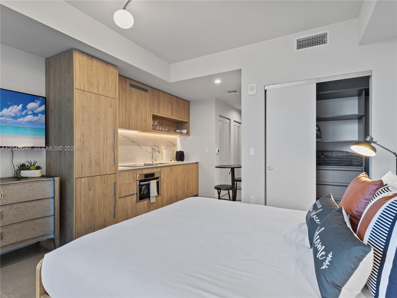 A studio apartment features a kitchenette with wood cabinetry, a bed, and a walk-in closet — 11 NE 6th St # 2102, Miami FL 33132, MIAMI, FL