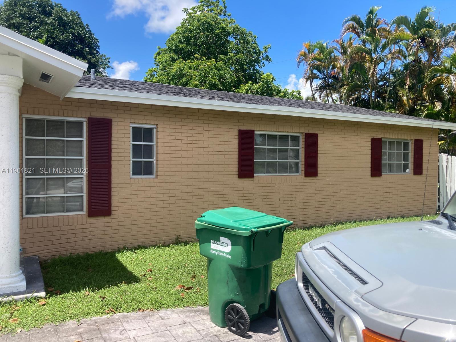 A tan brick house exterior features white-framed windows with red shutters and a paved driveway — 9905 Marlin RD, Cutler Bay FL 33157, CUTLER BAY, FL