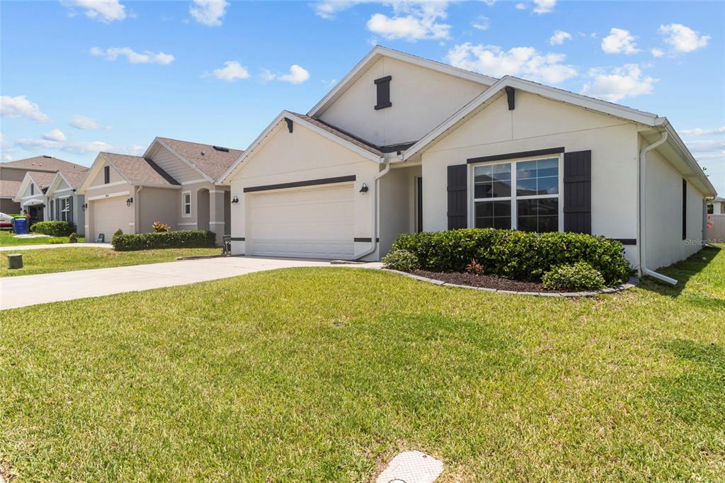 A single-story house with a white stucco exterior, a two-car garage, and a front lawn — 38386 SONNET LANDING AVENUE, ZEPHYRHILLS, FL