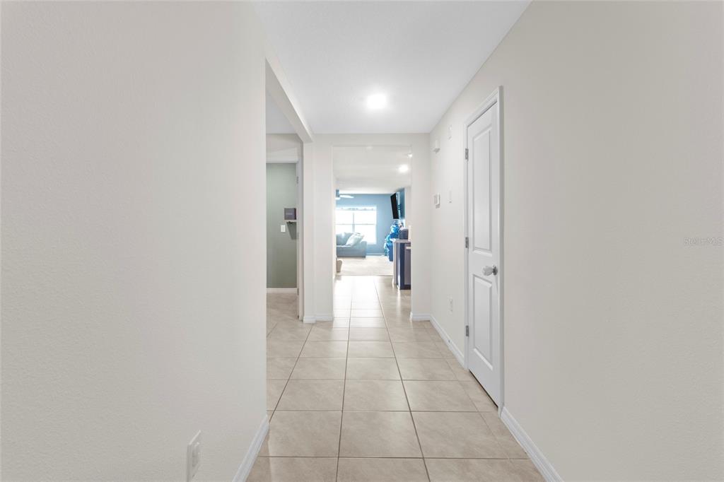 A tiled hallway leads to an open living area with light walls and white doors — 38386 SONNET LANDING AVENUE, ZEPHYRHILLS, FL