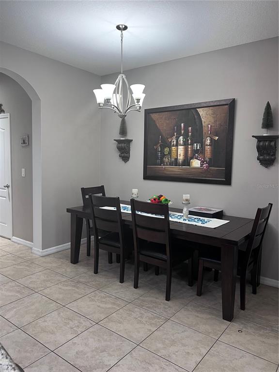 A dining room features a dark wood table, matching chairs, a chandelier, and wall art — 10426 YELLOW SPICE COURT, RIVERVIEW, FL