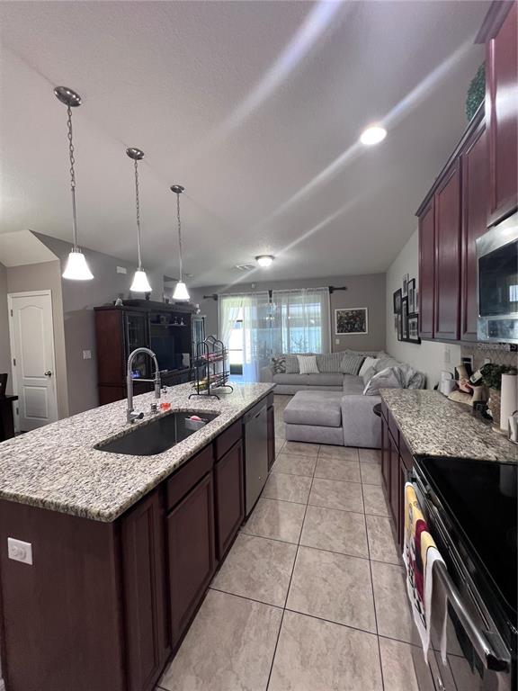 A kitchen with dark cabinets and granite countertops overlooks a living area with a sectional — 10426 YELLOW SPICE COURT, RIVERVIEW, FL