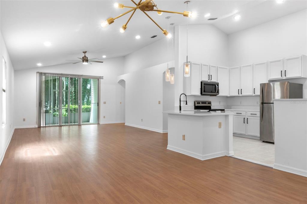 An open-concept kitchen with white cabinets and stainless steel appliances overlooks a spacious living area — 287 MARSH LANDING CIRCLE, DEBARY, FL